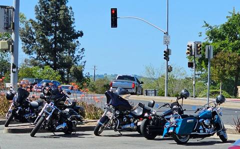 Several motorcycles and riders waiting at an intersection.