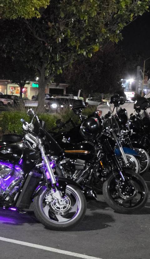 Motorcycles gathered outdoors after dark.