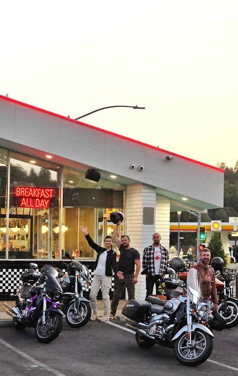 Riders gathered with motorcycles outside a roadside shop.