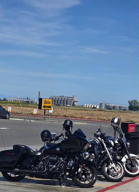 Motorcycles parked beside a road beneath a blue sky.