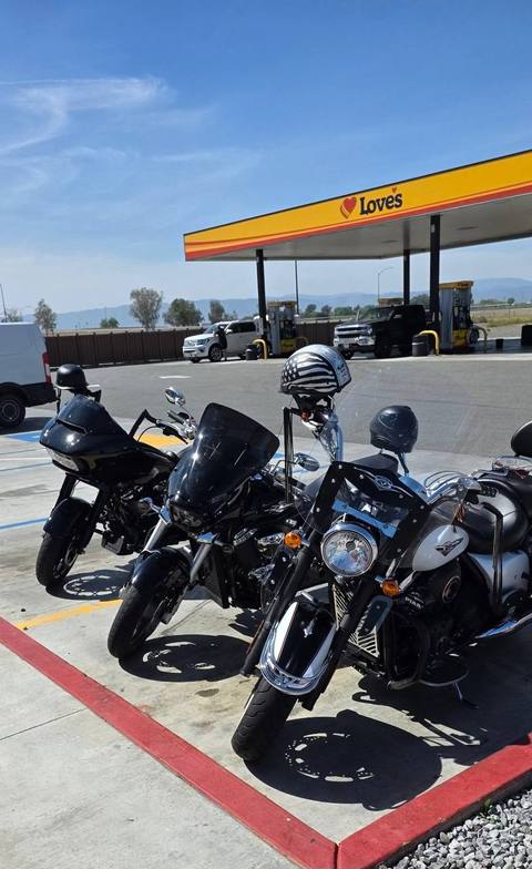 Motorcycles parked beneath a fuel-station canopy.