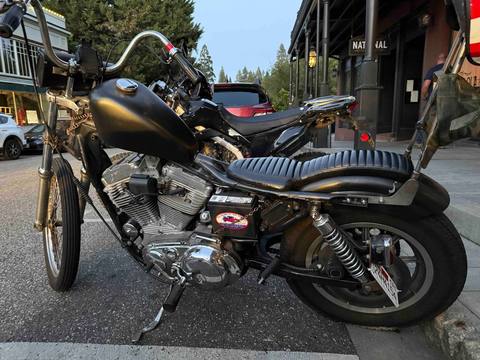 A motorcycle parked along a street near storefronts.
