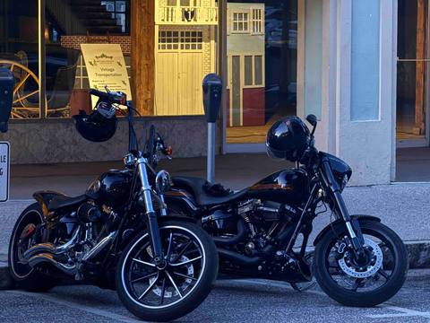 Two motorcycles parked outside a storefront in evening light.