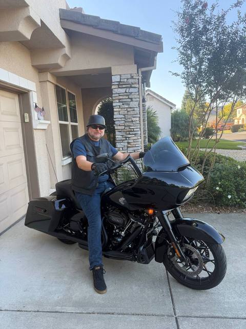 A rider seated on a black motorcycle outside a building.