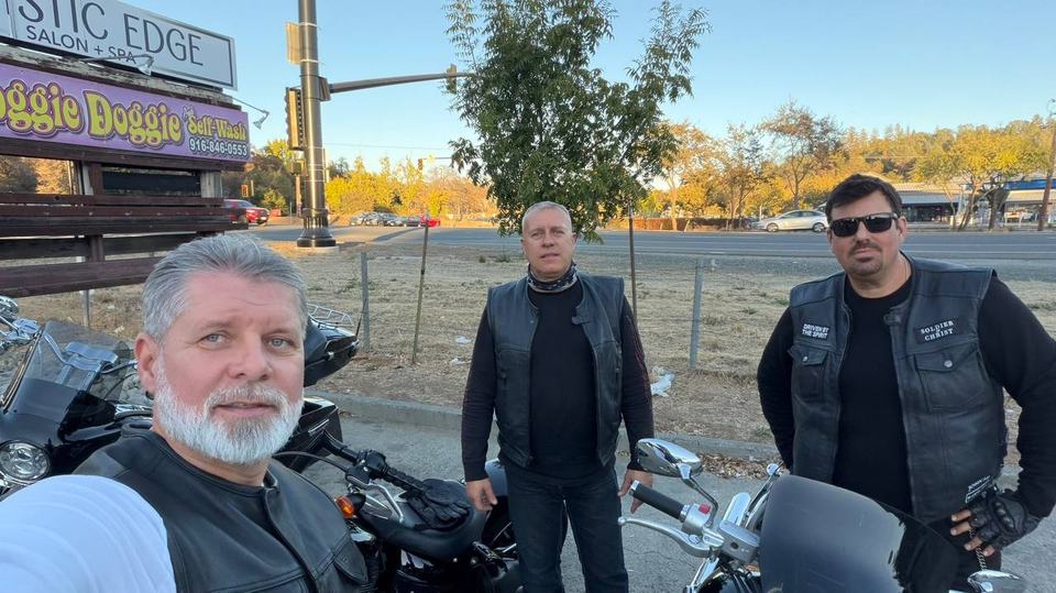 Three riders together beside their motorcycles.
